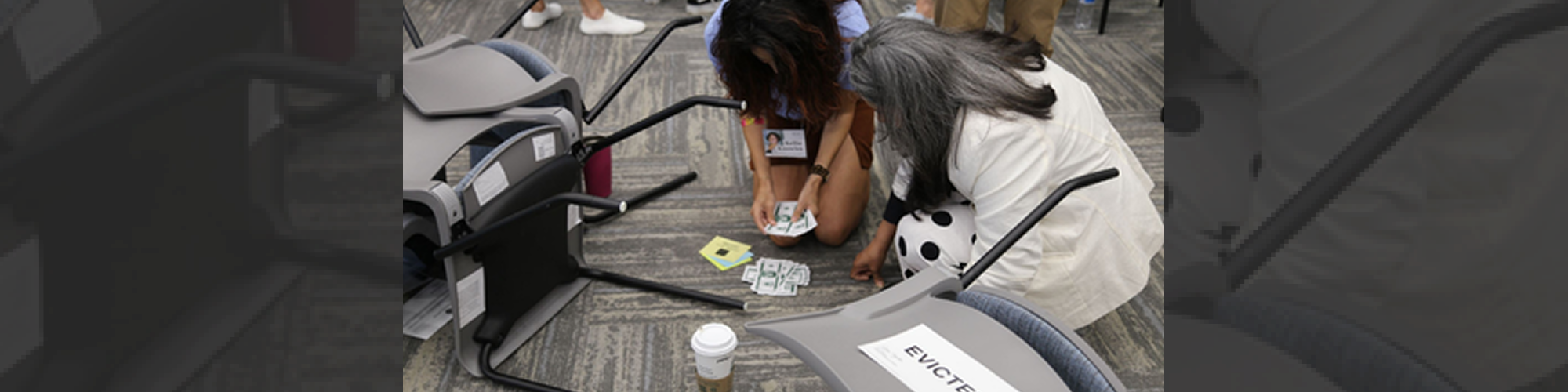 Two people counting cash beside overturned chairs