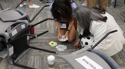 Two people counting cash beside overturned chairs